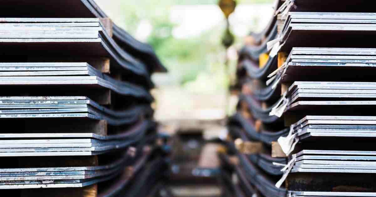 Neatly stacked metal sheets arranged in a warehouse for industrial use.